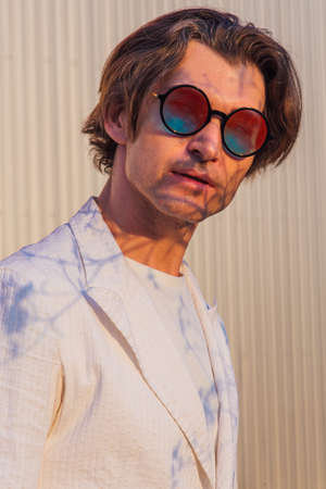 Close up portrait of a handsome man with round hippie sunglasses during sunsetの写真素材