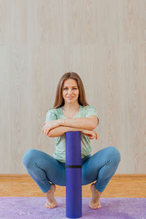 Young caucasian woman dressed in a blue leggins and t-shirt doing yoga asanas at home. Fitness and healthy lifestyle concept.の写真素材