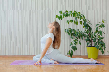 Young caucasian woman doing yoga asanas at home.の写真素材