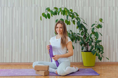Young caucasian woman dressed in a blue leggins and t-shirt doing yoga asanas at home. Fitness and healthy lifestyle concept.の写真素材