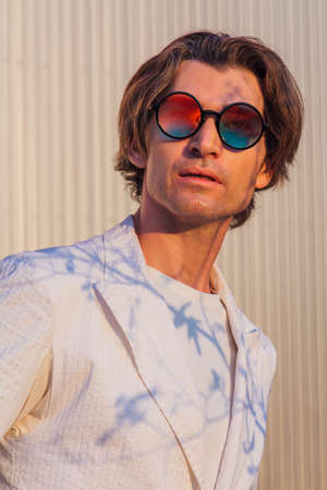 Close up portrait of a handsome man with round hippie sunglasses during sunsetの写真素材