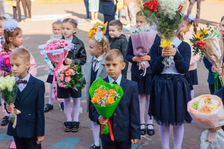 NOVOKUZNETSK, KEMEROVO REGION, RUSSIA - SEP, 1, 2021: Meeting with the first-grade pupils and teacher at schoolyard. The day of knowledge in Russia.のeditorial素材