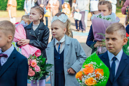 NOVOKUZNETSK, KEMEROVO REGION, RUSSIA - SEP, 1, 2021: Meeting with the first-grade pupils and teacher at schoolyard. The day of knowledge in Russia.のeditorial素材