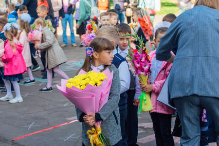 NOVOKUZNETSK, KEMEROVO REGION, RUSSIA - SEP, 1, 2021: Meeting with the first-grade pupils and teacher at schoolyard. The day of knowledge in Russia.のeditorial素材