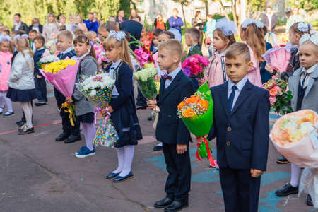 NOVOKUZNETSK, KEMEROVO REGION, RUSSIA - SEP, 1, 2021: Meeting with the first-grade pupils and teacher at schoolyard. The day of knowledge in Russia.のeditorial素材