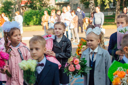 NOVOKUZNETSK, KEMEROVO REGION, RUSSIA - SEP, 1, 2021: Meeting with the first-grade pupils and teacher at schoolyard. The day of knowledge in Russia.のeditorial素材