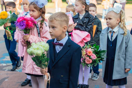 NOVOKUZNETSK, KEMEROVO REGION, RUSSIA - SEP, 1, 2021: Meeting with the first-grade pupils and teacher at schoolyard. The day of knowledge in Russia.のeditorial素材