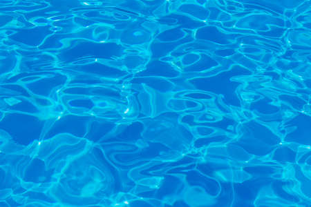 Swimming pool water surface with sparkling light reflections. aqua background.の写真素材
