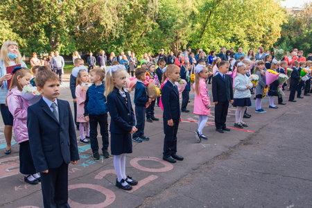 NOVOKUZNETSK, KEMEROVO REGION, RUSSIA - SEP, 1, 2021: Meeting with the first-grade pupils and teacher at schoolyard. The day of knowledge in Russia.のeditorial素材