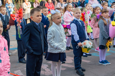 NOVOKUZNETSK, KEMEROVO REGION, RUSSIA - SEP, 1, 2021: Meeting with the first-grade pupils and teacher at schoolyard. The day of knowledge in Russia.のeditorial素材