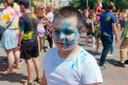 Novokuznetsk, Kemerovo region, Russia - June 12, 2022 :: Boy with colorful face painted with holi powder having fun outdoors.のeditorial素材