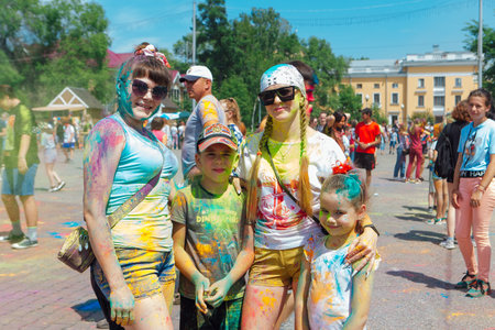 Novokuznetsk, Kemerovo region, Russia - June 12, 2022 :: Happy family with colorful faces painted with holi powder having fun outdoors.のeditorial素材