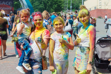 Novokuznetsk, Kemerovo region, Russia - June 12, 2022 :: Happy family with colorful faces painted with holi powder having fun outdoors.のeditorial素材