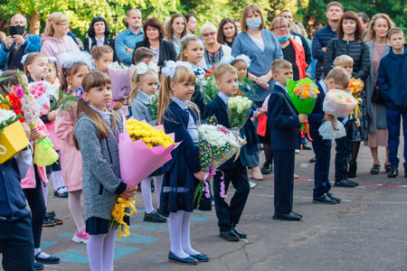 NOVOKUZNETSK, KEMEROVO REGION, RUSSIA - SEP, 1, 2021: Meeting with the first-grade pupils and teacher at schoolyard. The day of knowledge in Russia.のeditorial素材