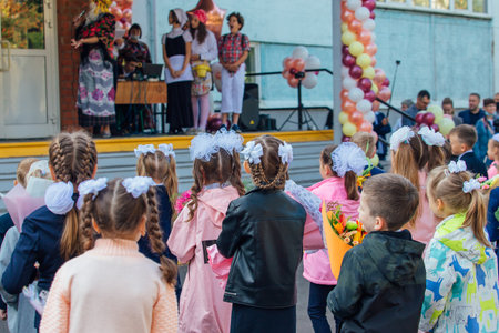 NOVOKUZNETSK, KEMEROVO REGION, RUSSIA - SEP, 1, 2021: Meeting with the first-grade pupils and teacher at schoolyard. The day of knowledge in Russia.のeditorial素材