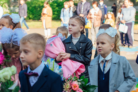 NOVOKUZNETSK, KEMEROVO REGION, RUSSIA - SEP, 1, 2021: Meeting with the first-grade pupils and teacher at schoolyard. The day of knowledge in Russia.のeditorial素材