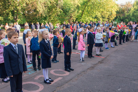 NOVOKUZNETSK, KEMEROVO REGION, RUSSIA - SEP, 1, 2021: Meeting with the first-grade pupils and teacher at schoolyard. The day of knowledge in Russia.のeditorial素材