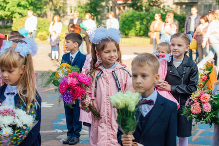 NOVOKUZNETSK, KEMEROVO REGION, RUSSIA - SEP, 1, 2021: Meeting with the first-grade pupils and teacher at schoolyard. The day of knowledge in Russia.のeditorial素材