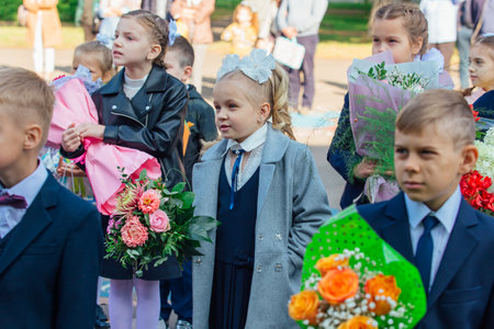 NOVOKUZNETSK, KEMEROVO REGION, RUSSIA - SEP, 1, 2021: Meeting with the first-grade pupils and teacher at schoolyard. The day of knowledge in Russia.のeditorial素材