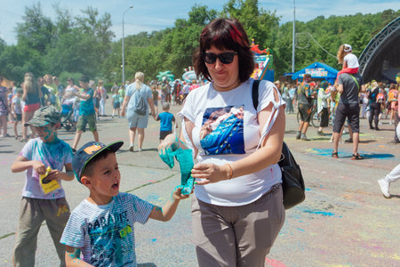 Novokuznetsk, Kemerovo region, Russia - June 12, 2022 :: Mother and son with colorful faces painted with holi powder having fun outdoors.のeditorial素材