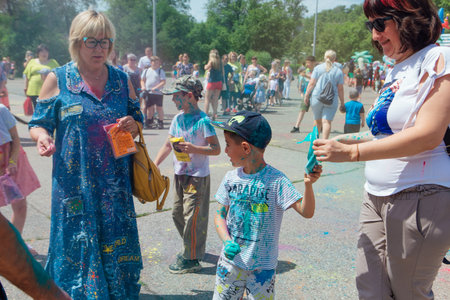 Novokuznetsk, Kemerovo region, Russia - June 12, 2022 :: Happy family with colorful faces painted with holi powder having fun outdoors.のeditorial素材