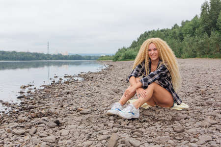 Young beautiful woman sitting on the river shoreの写真素材