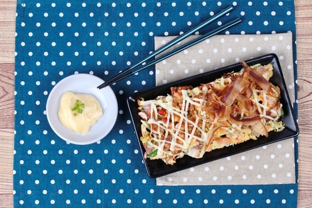 Japan pizza as "Okonomiyaki" is fried mixed vegetable flour with meat topped sweet sauce ,mayonnaise or salad cream and sliced dried yellowfin tuna served with side dish.の写真素材