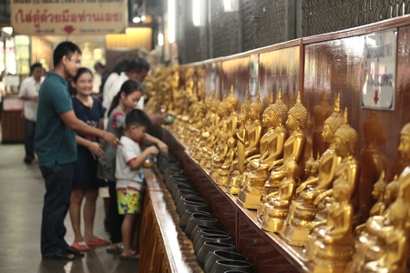 Chachoengsao,Thailand-October 15,Family pay coins in 109 monk bowls next Buddha images in Buddhist worship way at Wat Sothon Wararam Worawihan on October 15,2016 ,Thailand. Selective focus.のeditorial素材