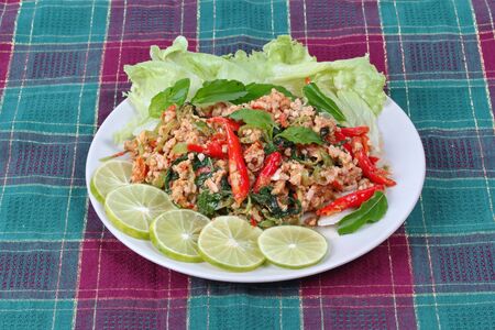 Popular Thai food,Fried spicy basil with minced pork topped sliced green lemon and and lettuce .の写真素材