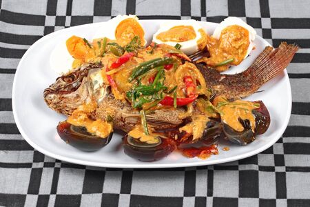 Curry-fried  tilapia fish with preserved egg and salted egg.の写真素材