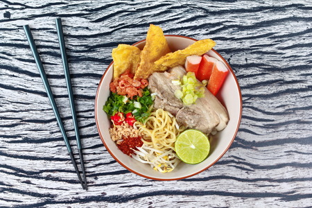 Spicy sour Ramen (Japanese noodle) soup as "tom yam " topped  steamed streaky pork,wonton,chili ,green lemon ,crab stick,dried shrimp,minced roast nut ,bean sprouts and shallot in pork's bone soup.の写真素材
