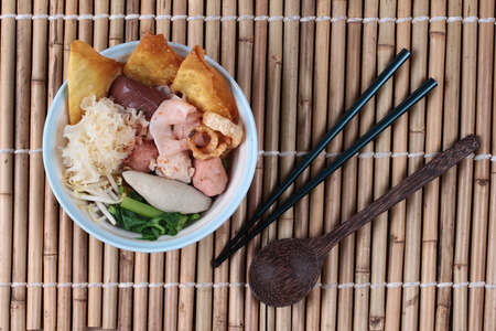 Thai noodle with pink tofu soup topped rugby fishball,wonton,porkball,boiled porkblood,pork rind,coriander and white mushroom call  Yen Ta Fo in Thaiの写真素材