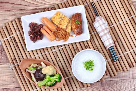 Rice gruel served with dish of  sausage ,spicy clams,sweet radish , omelet and spicy caned mackerel and  fried mixed vegetable. の写真素材