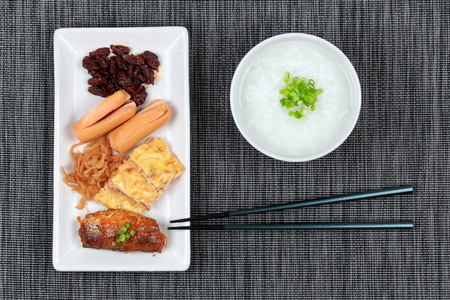 Rice gruel served with side dish as sausage ,spicy clams,sweet radish , omelet and spicy caned mackerel.の写真素材