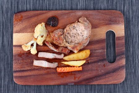 Pork steak with sliced carrot ,potato ,corn ,broccoli and cauliflower on butcher served.