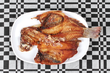 Thai cuisine ,Deep fried tilapia fish call Pla Nil Tod in Thai topped  crispy red onion. の写真素材