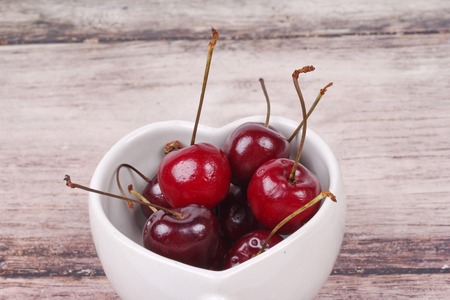 Cherries Chile and Heart-shaped mug isolated on wooden background.  Cherry ,good for heart.