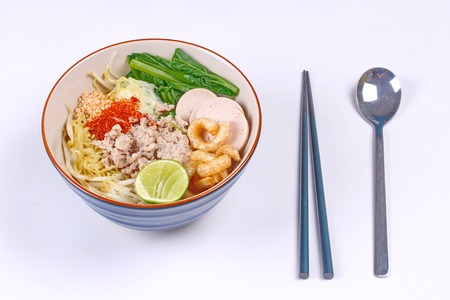 Two tone noodle ,white and yellow, with tom yum topped minced pork ,chili ,minced nut ,boiled kale , sliced Thai white pork sausage ,green lemon and crispy pork rind.の写真素材