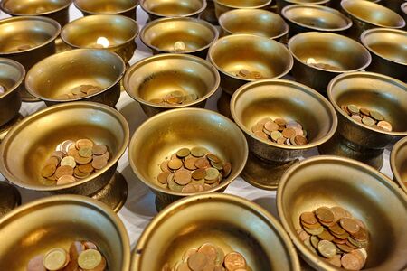 Buddhists make merit,Pay coins in 109 monk bowls  in Buddhist worship way . Selective focus.  の写真素材