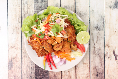 Spicy crispy deep-fried chicken salad with roll green mango call Kai Zap Yum Mamoung in Thai.の写真素材