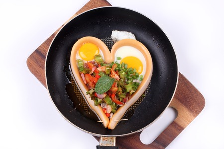 Homemade ,Sausage cheese in heart style wrap sunny up egg topped spicy sour wing bean salad in pan served for Valentine festivalの写真素材