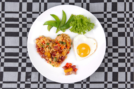 Colorful Chinese sausage fried rice and sunny egg in heart shapes with mixed vegetable as peas, pumpkin, taro, tomatoes, carrots and sweet peppers.の写真素材