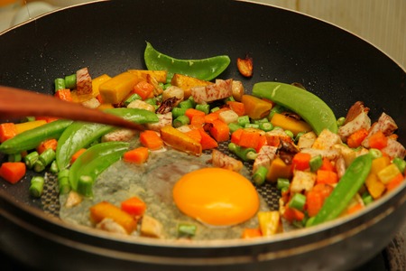Homemade cooking of Chinese sausage fried rice and sunny egg in heart shapes with mixed vegetable as peas, pumpkin, taro, tomatoes, carrots and sweet peppers.の写真素材