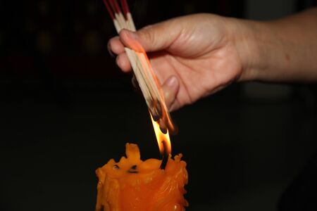 Buddhists make merit,Placing a lighted candle and lit incense with candles frame on the altar of Buddha  at temple.  Selective focus.の写真素材