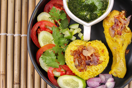 Muslim yellow jasmine rice with chicken,Halal chicken and curry rice topped slice cucumber ,tomato ,red onion and sweet chili sauce call Khao Mok Kai in Thai,Halal foodの写真素材