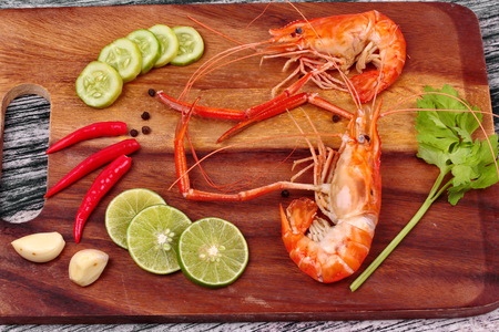 Ready streamed large fresh prawns in heart shape and spicy sour herb  on butcher servedの写真素材
