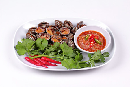 Fresh and delicious soft-boiled blood cockles shell  topped red chili ,coriander and Chinese celery served with spicy sauce  in Korea pattern black dishの写真素材