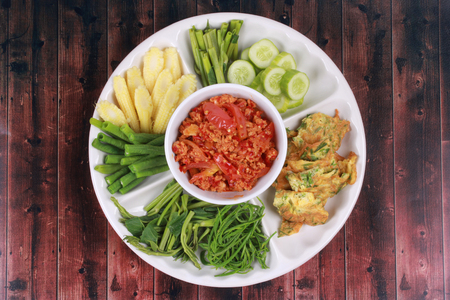 Thai recipe,Spicy meat and tomato dip call Nam Prik Ong in Thai ,served with herb omlete,boiled morning glory,sliced cucumber,corn,acasia and cow-pea.の写真素材