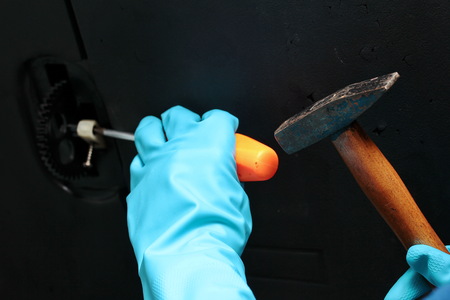 Technician wear rubber grove to use hammer to hit screwdriver for machine maintenance.の写真素材