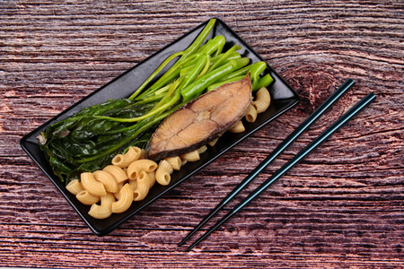 Fusion Food ,Fried Chinese kale and macaroni with garlic in oyster sauce topped the deep-fried dried salted sea fish served on Japanese pattern dish.の写真素材
